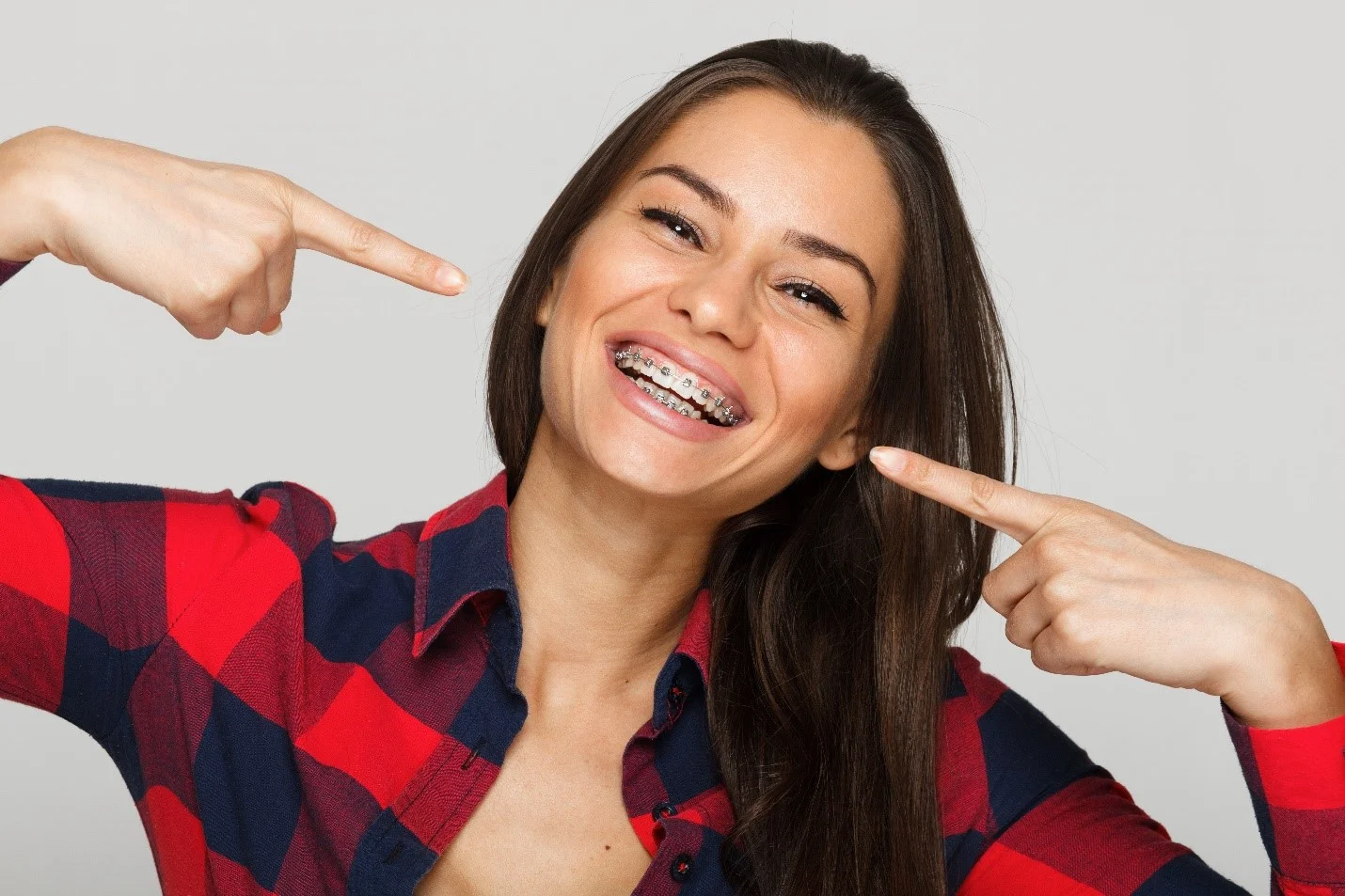 Smiling patient pointing at her braces